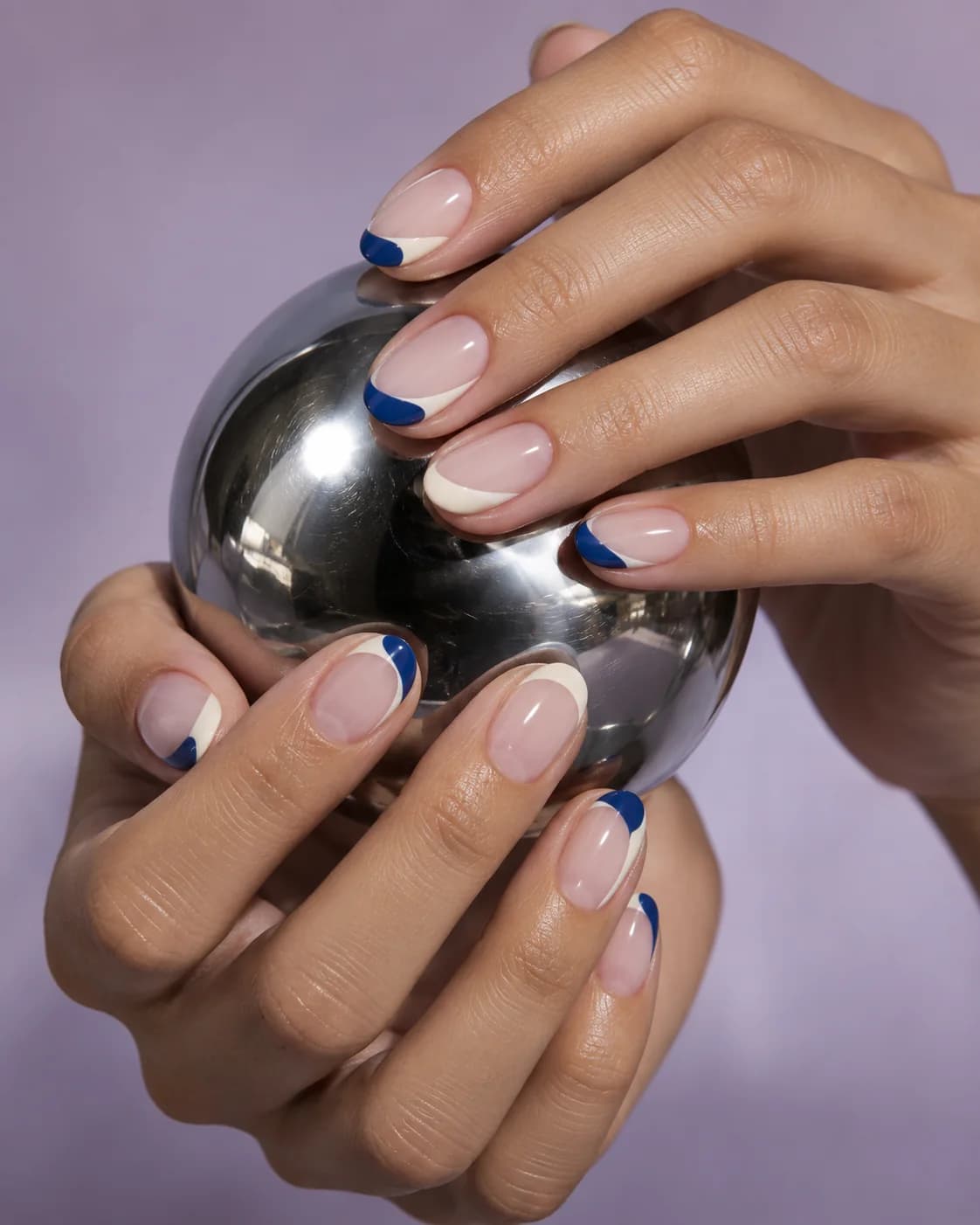Asymmetric cobalt and cream French manicure around a chrome sphere