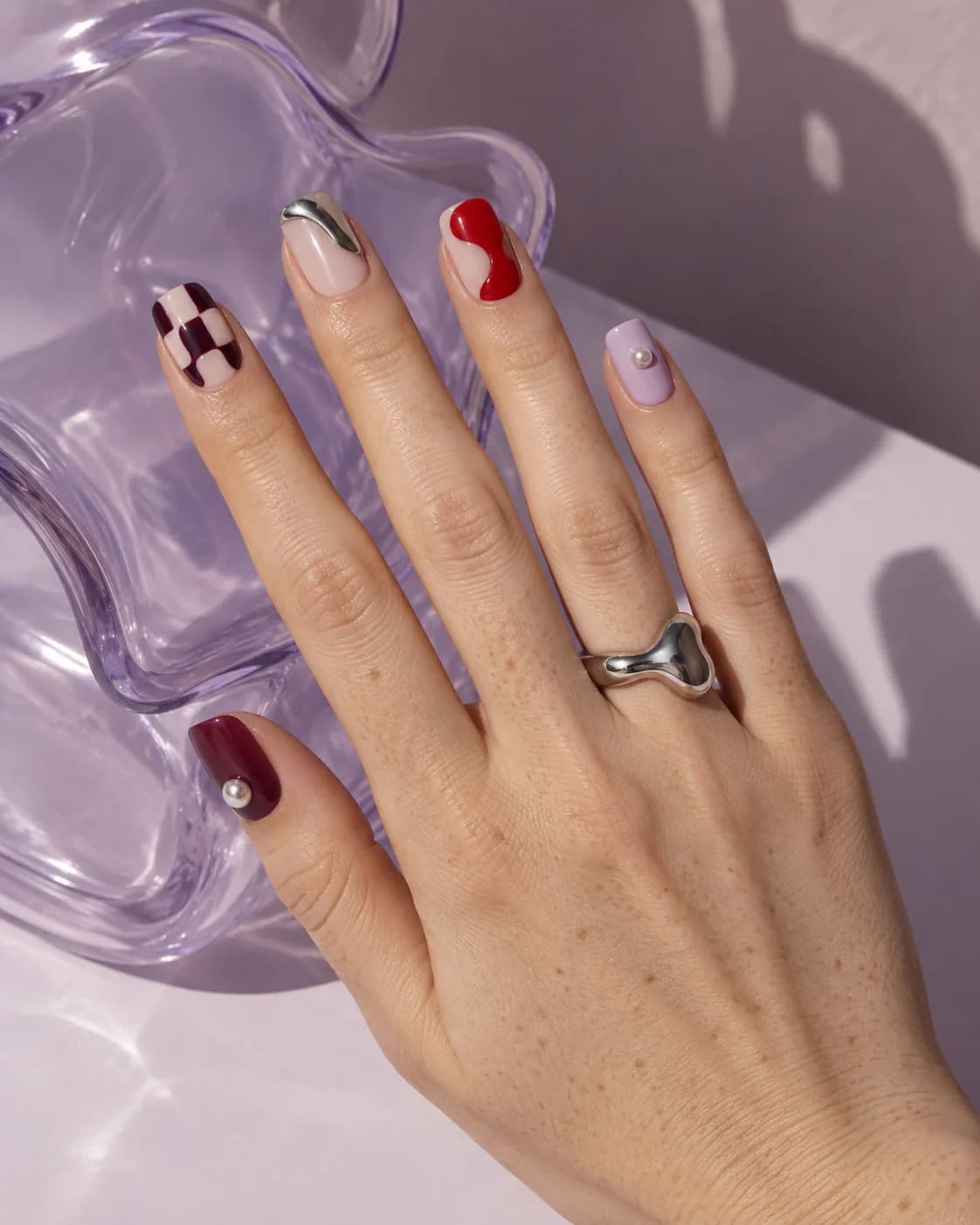 Statement nail art with chrome, checkerboard, pearl, and glossy red
